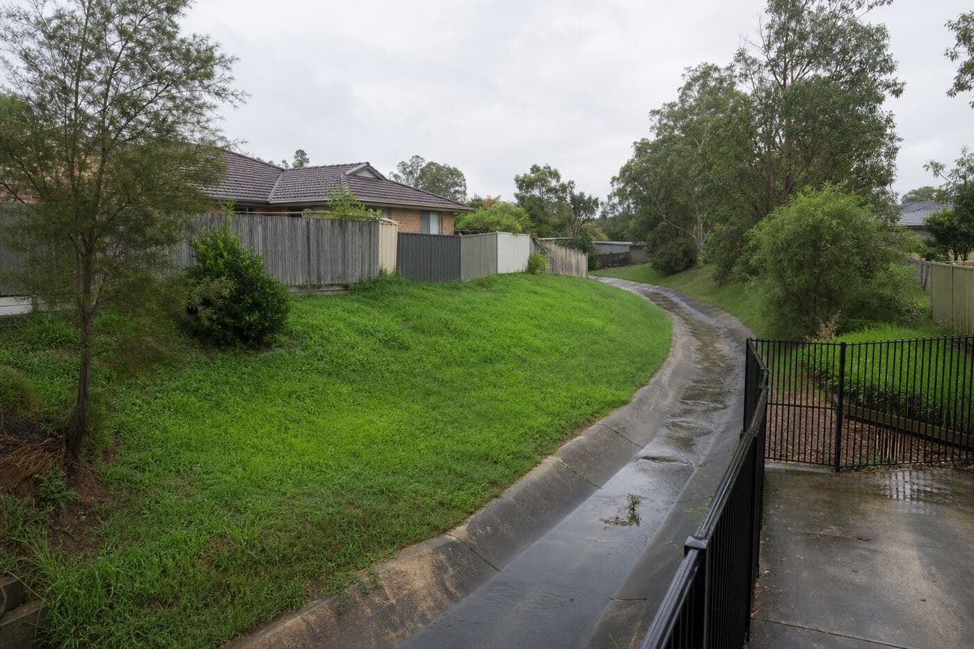 Stormwater corridor behind suburban houses after light rain
