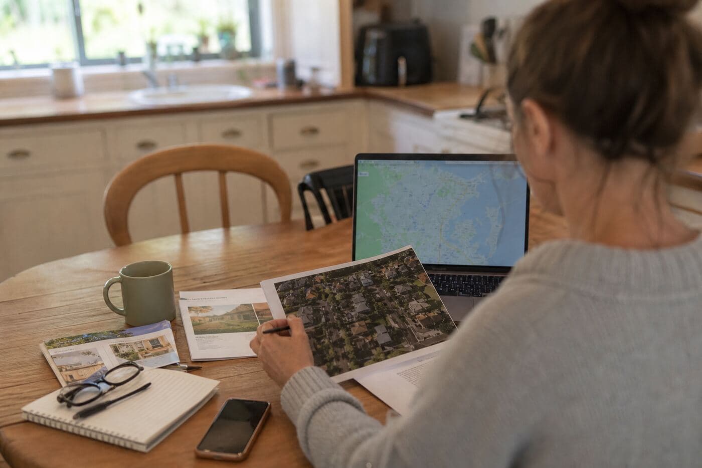 Buyer reviewing property documents and a suburb map at a kitchen table